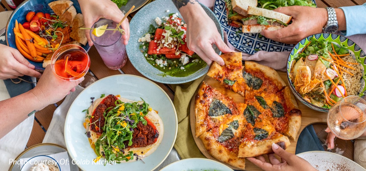 hands reaching over plates of food at colab kitchen in palm city